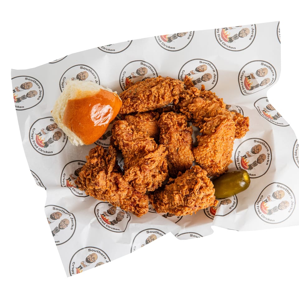 Crispy fried chicken pieces with a glossy bun and green pepper on Southern Jerks branded paper.