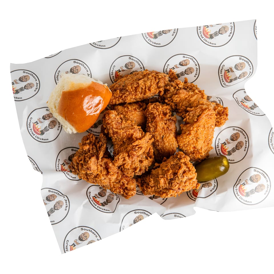 Crispy fried chicken pieces with a buttered bun and green pepper on Southern Jerks branded paper.
